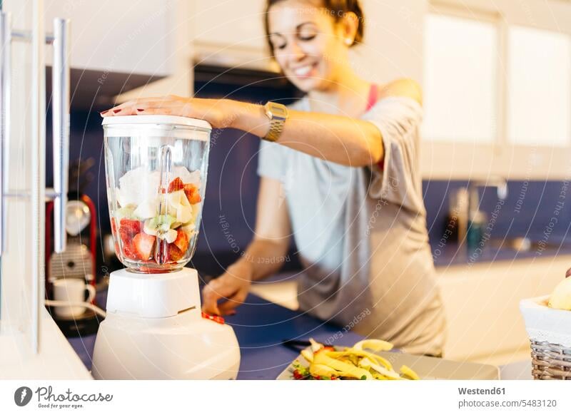 Junge Frau in der Küche bereitet ein gesundes Getränk im Mixer zu lächeln Smoothie Smoothies weiblich Frauen Getraenk Getränke Getraenke Food and Drink