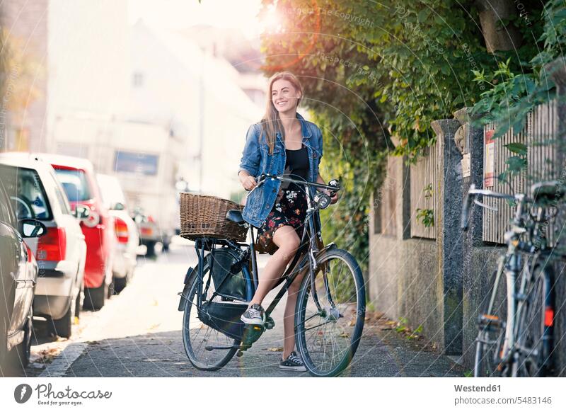 Junge Woan mit Fahrrad in der Stadt Bikes Fahrräder Räder Rad junge Frau junge Frauen Jeansjacke Jeansjacken radfahren fahrradfahren radeln Raeder Verkehrswesen