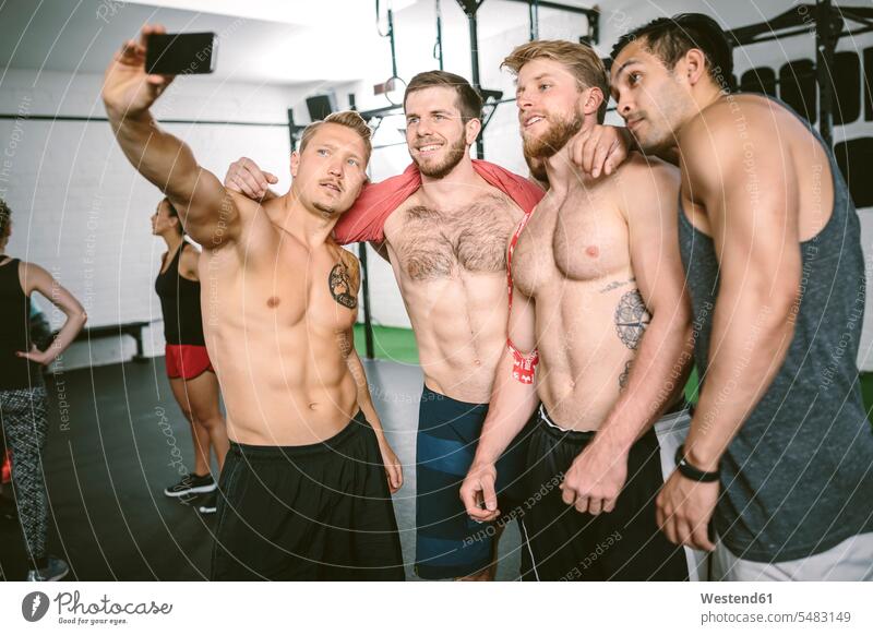 Vier Sportler im Fitnessstudio machen ein Selfie Waschbrettbauch Waschbrettbaeuche sixpack sixpacks Waschbrettbäuche muskulös Muskeln athletisch Sixpack