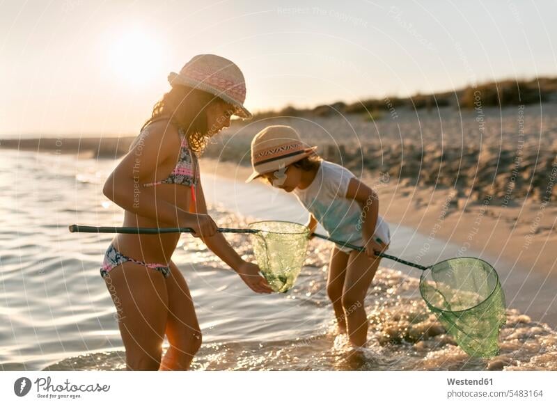 Spanien, Menorca, zwei Mädchen mit Dip-Netzen am Strand Schwester Schwestern spielen Kescher Beach Straende Strände Beaches weiblich Geschwister Familie