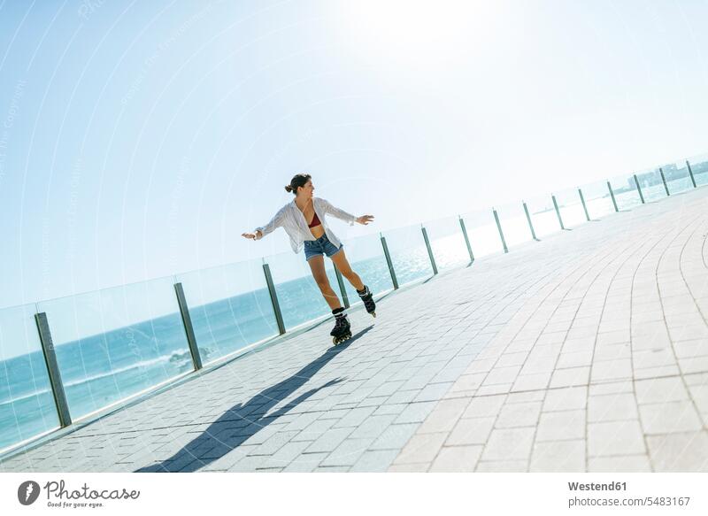 Junge Frau beim Inlineskaten auf der Strandpromenade an der Küste fahren Inlineskates Inline skates inline skate Inliner weiblich Frauen Rollerblades