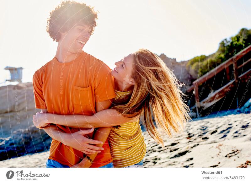 Verspieltes Paar am Strand glücklich Glück glücklich sein glücklichsein umarmen Umarmung Umarmungen Arm umlegen Beach Straende Strände Beaches Pärchen Paare