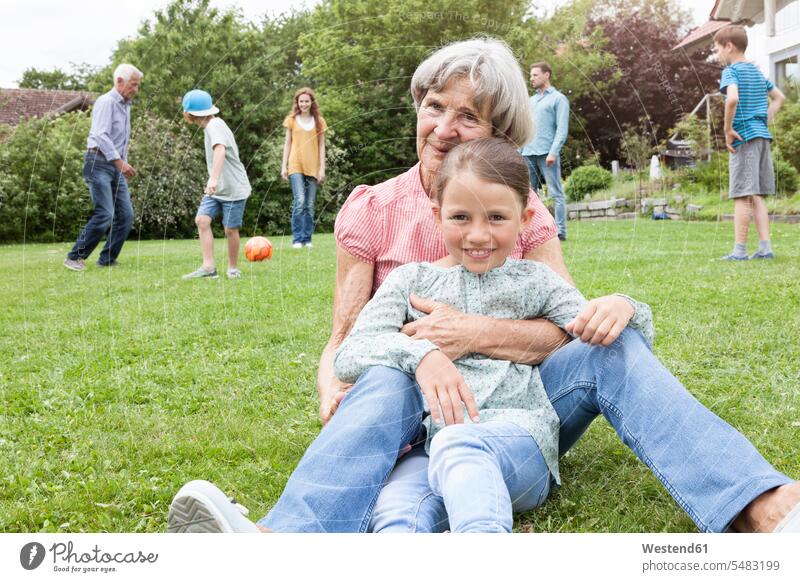 Porträt einer glücklichen Großmutter mit Enkelin und Familie im Hintergrund Portrait Porträts Portraits Familien lächeln Garten Gärten Gaerten Glück