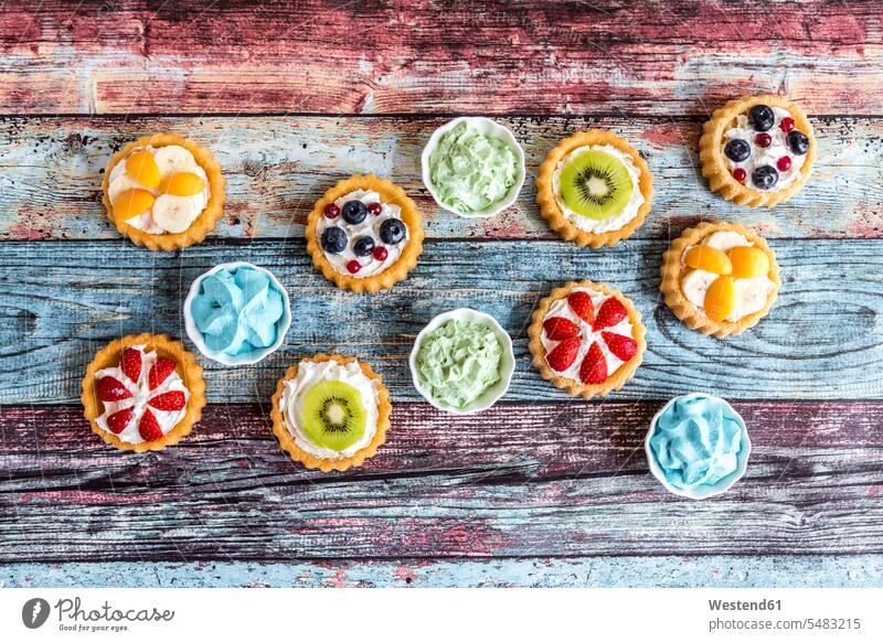 Mini-Kuchen mit Schlagsahne, garniert mit verschiedenen Früchten Stillleben Stillife still life Stills Stilleben Kreis kreisförmig kreisfoermig Kreise dekoriert