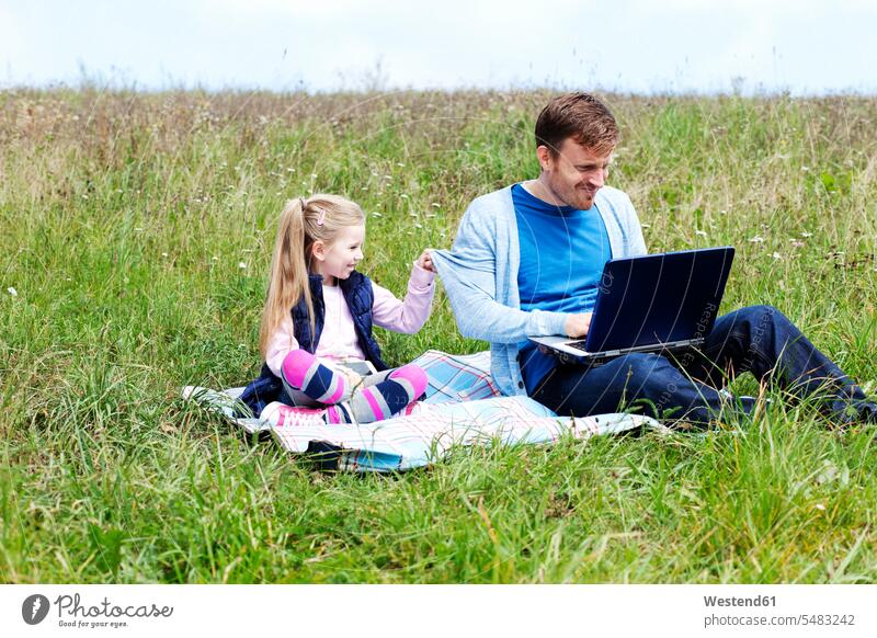 Vater und Tochter sitzen auf der Wiese, Smartphone und Laptop Europäer Kaukasier Europäisch kaukasisch Mobilität mobil Technologie Technologien Technik