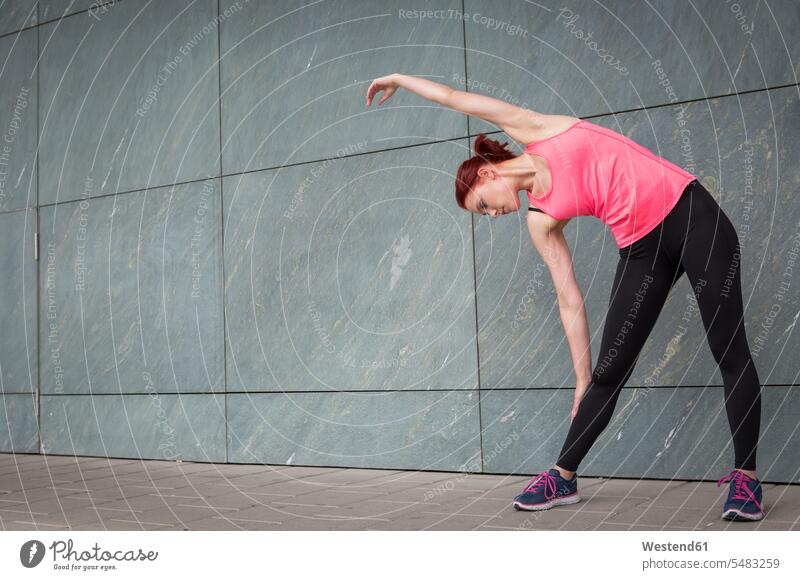 Junger Athlet beim Stretching im Freien Frau weiblich Frauen jung aufwärmen sich aufwärmen sich aufwaermen dehnen strecken trainieren Workout üben ausüben Übung
