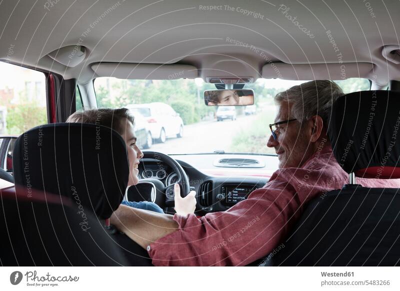 Vater lehrt Sohn Autofahren lächeln lehren unterrichten beibringen Wagen PKWs Automobil Autos Söhne üben ausüben Übung trainieren autofahren Papas Väter Vati