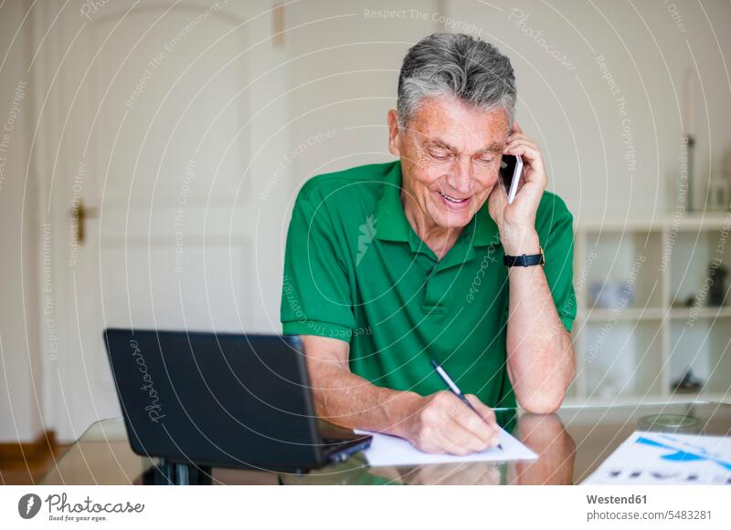 Älterer Mann sitzt am Schreibtisch und telefoniert am Handy Laptop Notebook Laptops Notebooks Senior ältere Männer älterer Mann Senioren telefonieren anrufen
