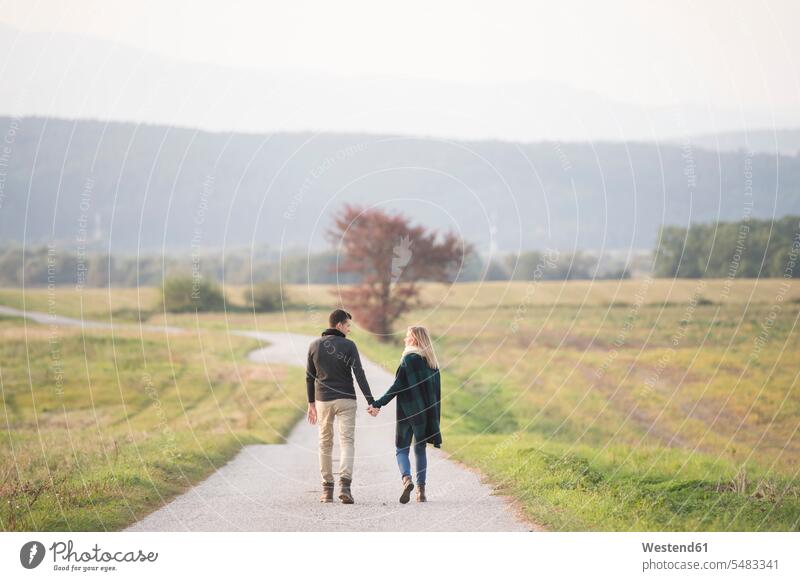 Junges Paar beim Spaziergang in ländlicher Landschaft gehen gehend geht Natur Pärchen Paare Partnerschaft Mensch Menschen Leute People Personen Abgeschiedenheit