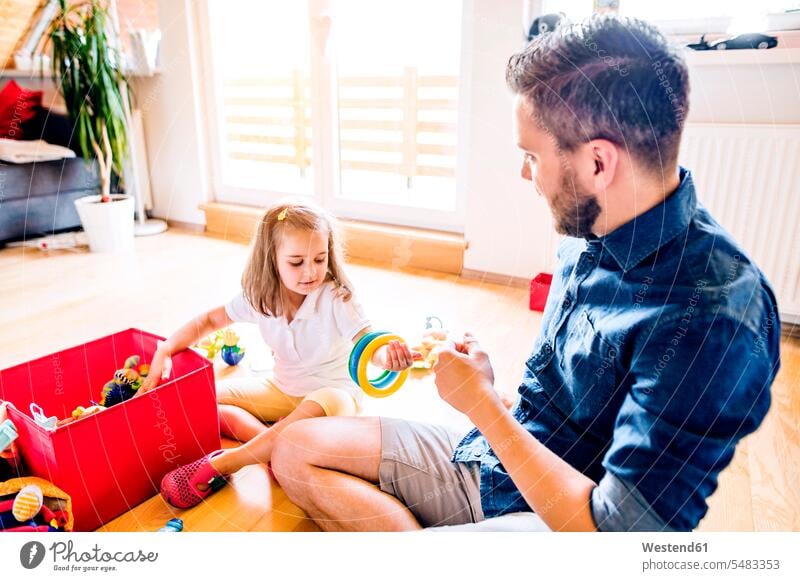 Vater und Tochter spielen gemeinsam mit Spielzeug Papas Väter Vati Vatis Papis Mädchen weiblich sitzen sitzend sitzt Töchter Eltern Familie Familien Mensch