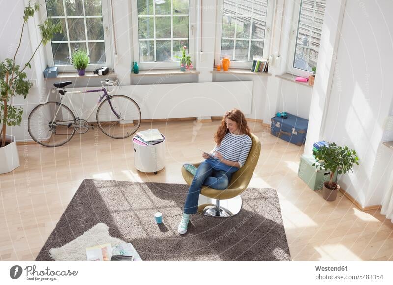 Frau zu Hause sitzt auf einem Stuhl und verwendet ein digitales Tablet lächeln Tablet Computer Tablet-PC Tablet PC iPad Tablet-Computer weiblich Frauen Sessel