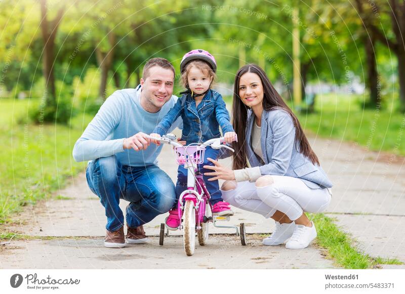 Lächelnde Eltern mit Tochter auf dem Fahrrad Mutter Mami Mutti Mütter Mama Familie Familien fahren Töchter lächeln Bikes Fahrräder Räder Rad Vater Papas Väter