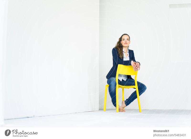 Geschäftsfrau sitzt auf einem gelben Stuhl und denkt Stuehle Stühle Geschäftsfrauen Businesswomen Businessfrauen Businesswoman sitzen sitzend Frau weiblich