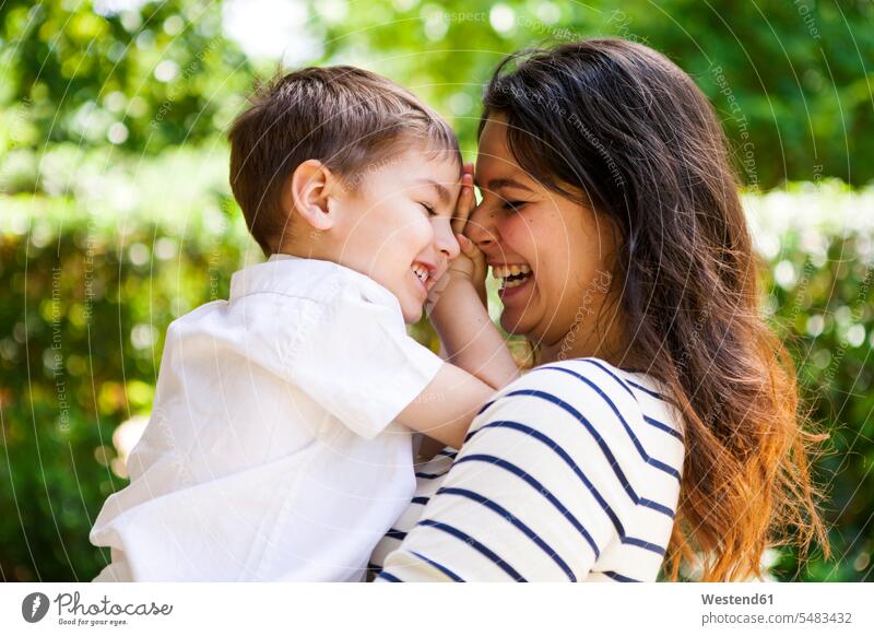 Glückliche Mutter und Sohn umarmen sich im Freien Mamas Mami Mutti Mütter Muetter Mamis Muttis glücklich glücklich sein glücklichsein Söhne lächeln Eltern