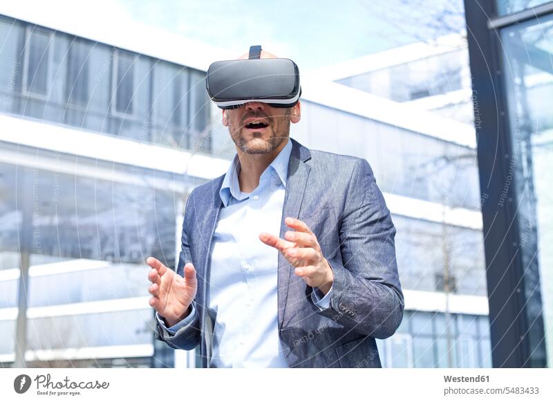 Mann mit Virtual-Reality-Brille im Freien Virtuelle Realität Virtuelle Realitaet VR Sinne greifen Griff ausstrecken ergreifen Oberkörper Oberkörperaufnahmen