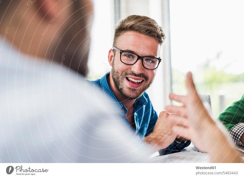 Zuversichtlicher junger Fachmann in einer Sitzung Meeting Business Meeting lächeln Mann Männer männlich Geschäftsbesprechung Besprechung Erwachsener erwachsen