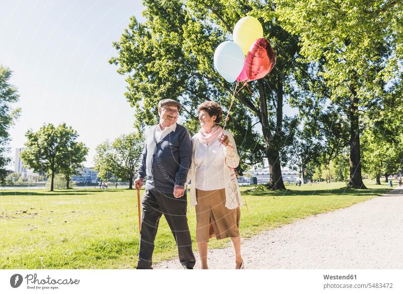 Glückliches älteres Ehepaar mit Ballons in einem Park spazieren Seniorenpaar älteres Paar Seniorenpaare ältere Paare Seniorenpärchen Luftballon Luftballons