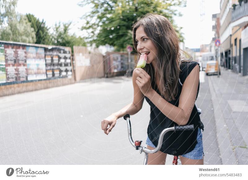 Frau mit Fahrrad isst Eis am Stiel weiblich Frauen Speiseeis essen essend Portrait Porträts Portraits lächeln Erwachsener erwachsen Mensch Menschen Leute People