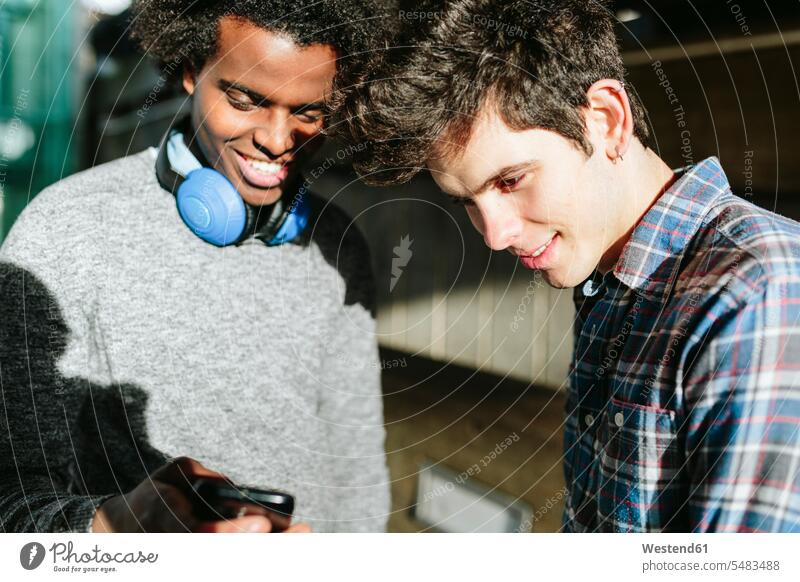 UK, London, zwei junge Männer sehen sich ihre Smartphones an Afroeuropäer Afro-Europäer Afroeuropäisch Afro-Europäisch Student Hochschueler Studierender