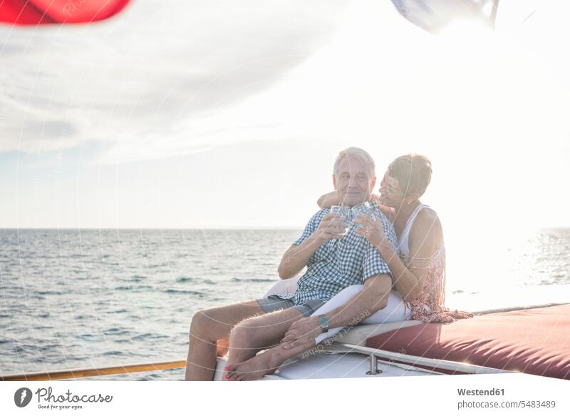Glückliches Paar bei einem Drink auf einer Bootsfahrt glücklich glücklich sein glücklichsein Pärchen Paare Partnerschaft Boote lächeln sitzen sitzend sitzt