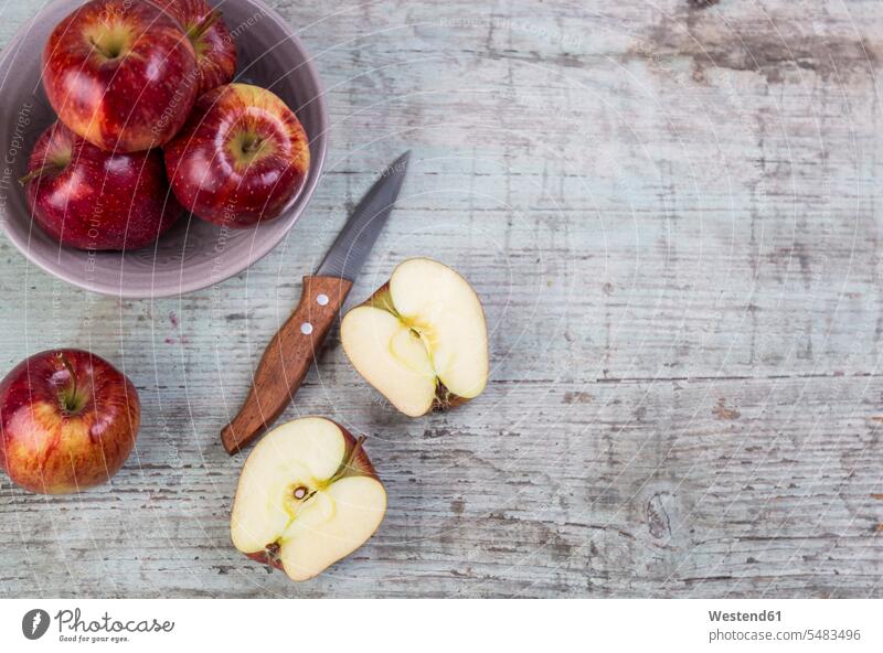 Ganze und in Scheiben geschnittene rote Äpfel und ein Küchenmesser auf Holz Shabby Chic vitaminreich glänzend glaenzend Glanz Stillleben Stillife still life