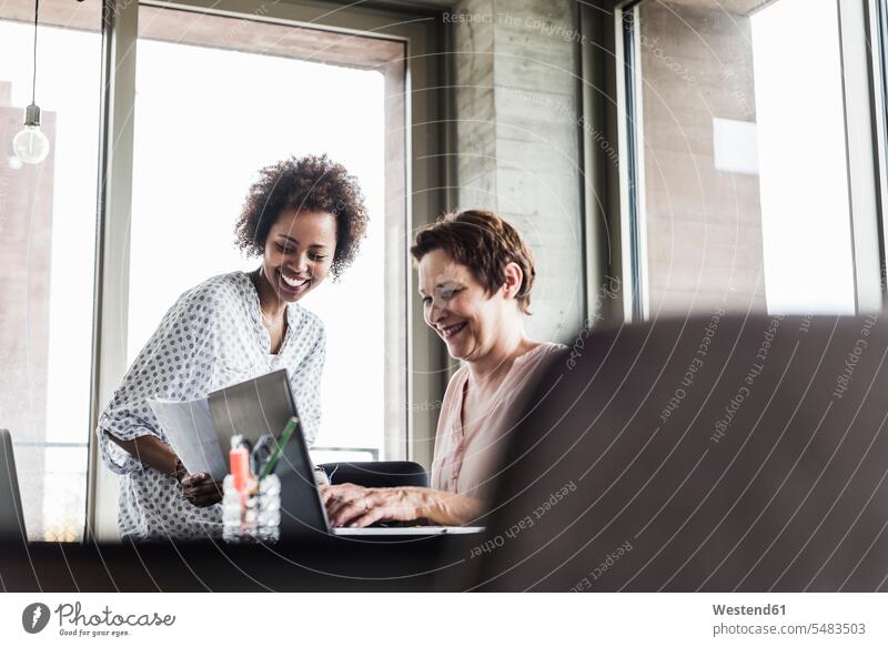 Zwei lächelnde Frauen arbeiten zusammen in einem Büro Office Büros Arbeit Kollegin Kolleginnen Arbeitsplatz Arbeitsstätte Arbeitstelle Kollegen Arbeitskollegen
