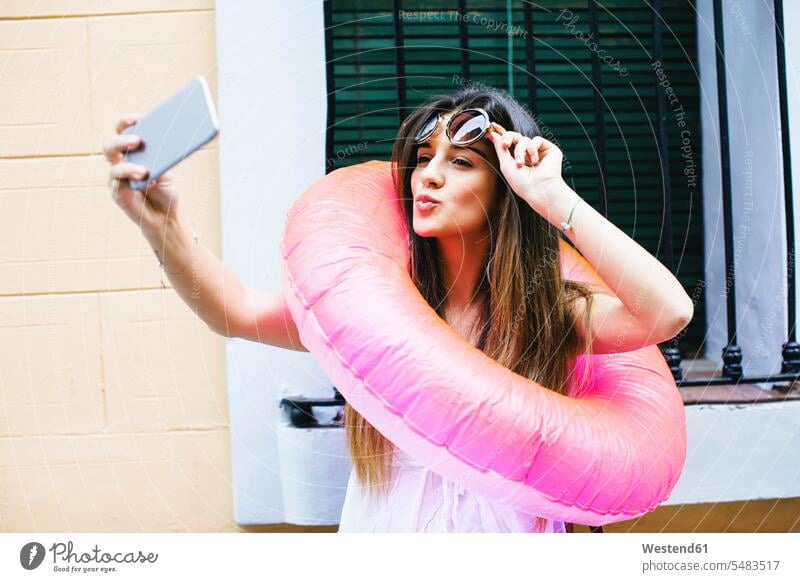 Junge Frau mit Badering um den Hals macht ein Selfie Selfies Schwimmring Handy Mobiltelefon Handies Handys Mobiltelefone weiblich Frauen Erwachsener erwachsen