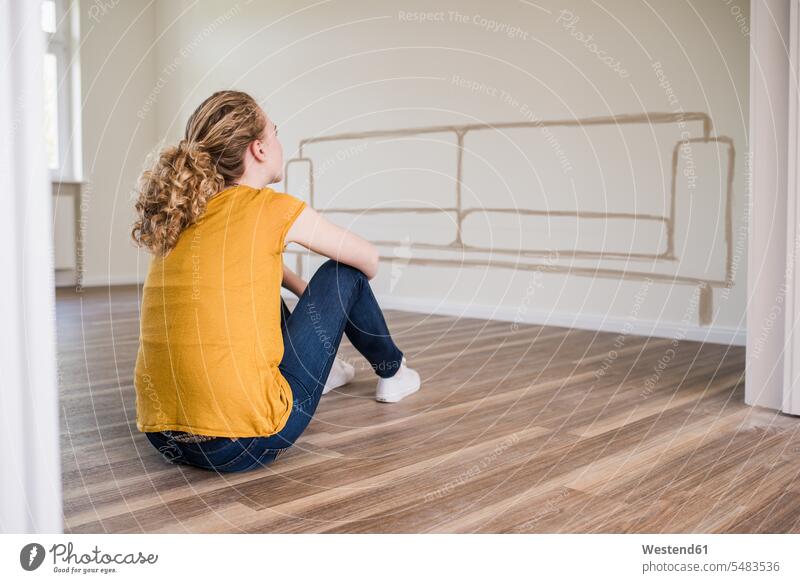 Junge Frau in neuer Wohnung sitzt auf dem Boden und denkt über Innenarchitektur nach Sofa Couches Liege Sofas weiblich Frauen wohnen Wohnungen sitzen sitzend