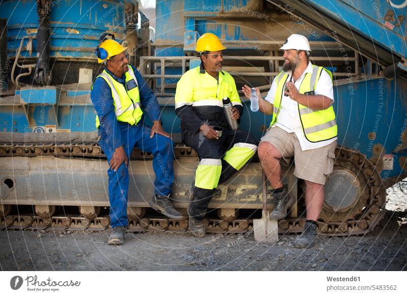 Kollegen im Steinbruch, die auf der Maschine sitzen und eine Pause machen Arbeiter Kiesgrube Schutzkleidung Leuchtweste Tagebau arbeiten Tagebaubetrieb Bergbau