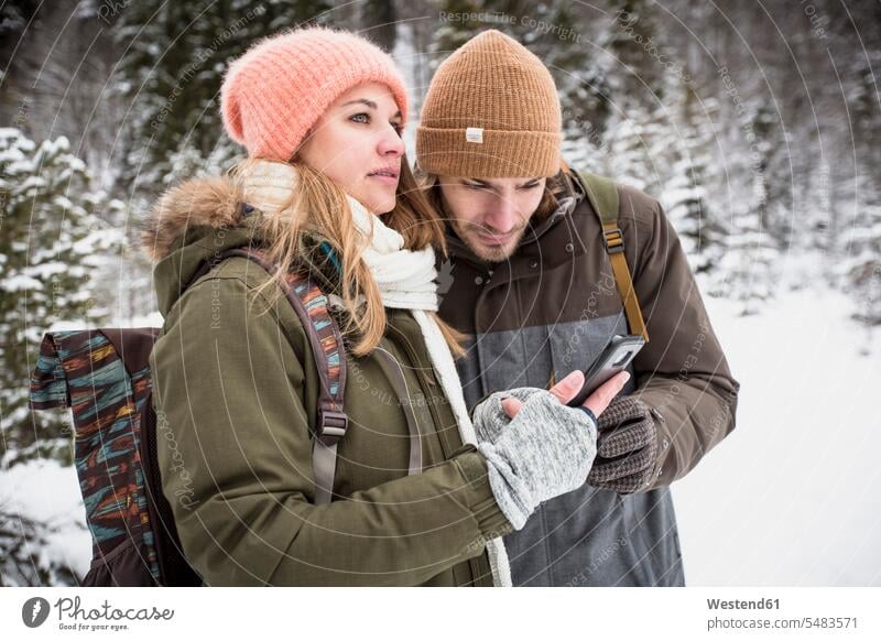 Ehepaar auf einer Reise im Winter mit dem Handy Paar Pärchen Paare Partnerschaft umherblicken umschauen umsehen Ausflug Ausflüge Kurzurlaub Ausfluege winterlich