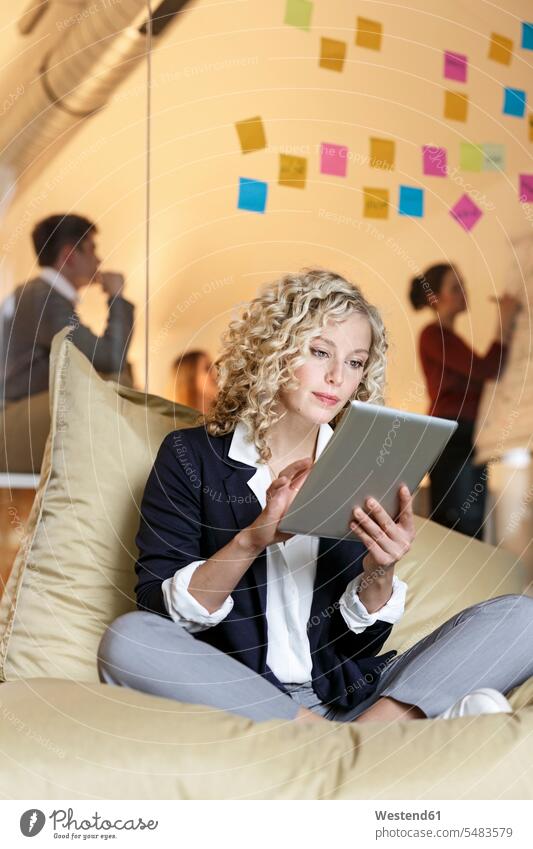 Frau im Büro mit Tablette im Sitzungssacker mit Besprechung im Hintergrund Office Büros Meeting Business Meeting Tablet Computer Tablet-PC Tablet PC iPad