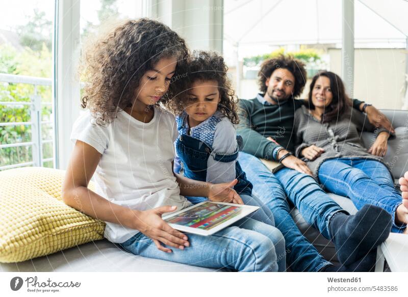 Glückliche Familie sitzt auf der Couch, die Tochter spielt mit dem digitalen Tablet Familien Tablet Computer Tablet-PC Tablet PC iPad Tablet-Computer sitzen