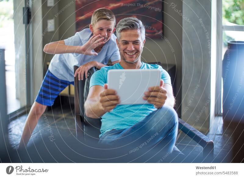 Glückliche Vater und Sohn mit digitalem Tablett zu Hause Papas Väter Vati Vatis Papis Tablet Computer Tablet-PC Tablet PC iPad Tablet-Computer lächeln Söhne