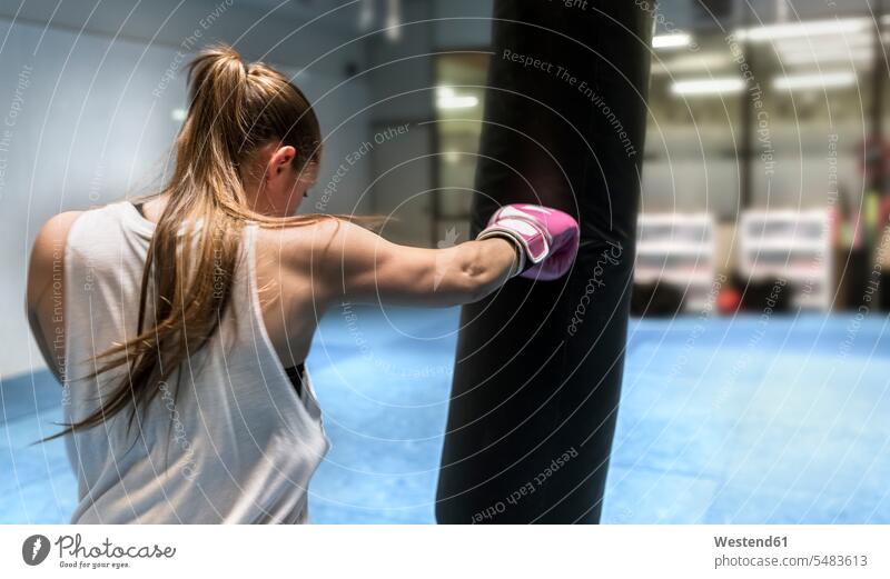 Junge Frau boxt im Fitnessstudio schlagen Selbstverteidigung Boxen Boxsport Boxkampf Boxkaempfe Boxkämpfe Fitnessclubs Fitnessstudios Turnhalle trainieren