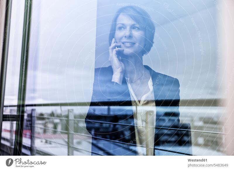 Geschäftsfrau am Handy hinter der Fensterscheibe Europäer Kaukasier Europäisch kaukasisch Telekommunikation Deutschland Verbindung verbunden verbinden Anschluss