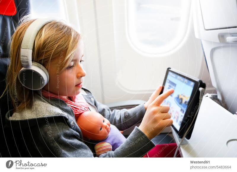 Kleines Mädchen sitzt im Flugzeug und sieht sich etwas auf einem digitalen Tablet an Flieger Flugzeuge weiblich Tablet Computer Tablet-PC Tablet PC iPad