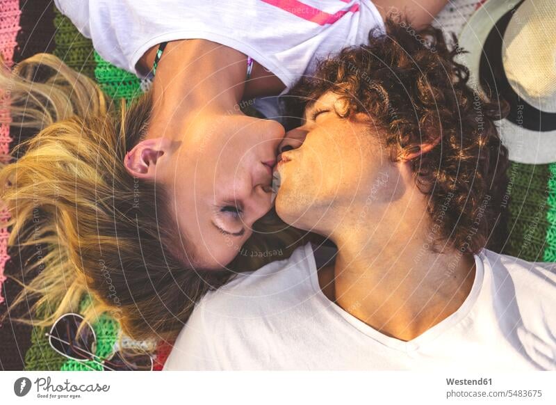 Junges Paar küsst sich auf Decke liegen liegend liegt küssen Küsse Kuss Pärchen Paare Partnerschaft Mensch Menschen Leute People Personen Decken zwei Personen 2