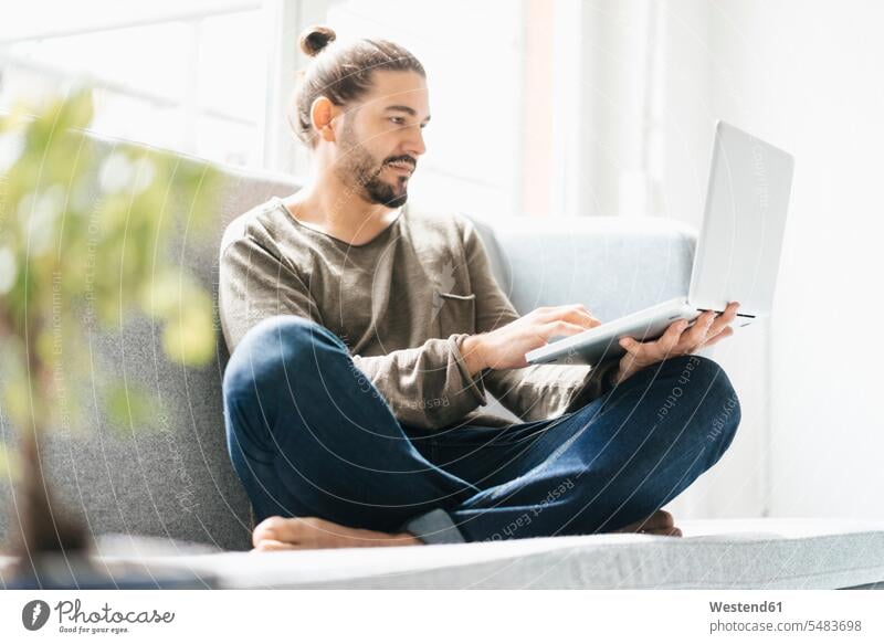 Porträt eines Mannes, der mit einem Laptop auf der Couch sitzt Männer männlich Notebook Laptops Notebooks Erwachsener erwachsen Mensch Menschen Leute People