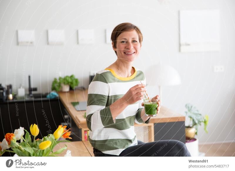 Porträt einer lächelnden Frau mit grünem Smoothie in der Küche weiblich Frauen Smoothies Portrait Porträts Portraits Erwachsener erwachsen Mensch Menschen Leute