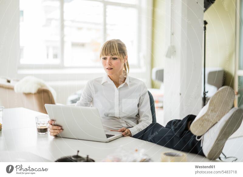 Geschäftsfrau mit Laptop im Büro mit Füßen auf dem Schreibtisch Notebook Laptops Notebooks Office Büros Arbeitstisch Schreibtische Geschäftsfrauen Businesswomen