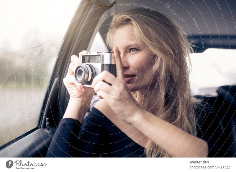 Frau sitzt im Auto und fotografiert mit der Kamera Wagen PKWs Automobil Autos weiblich Frauen fotografieren Portrait Porträts Portraits Kraftfahrzeug