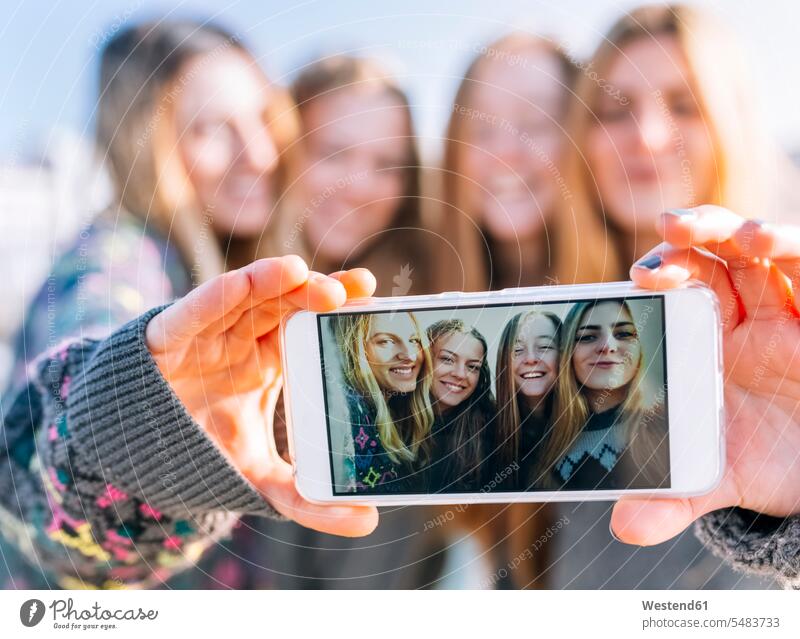 Gruppenbild von vier Freunden auf dem Display eines Smartphones, Nahaufnahme Freundinnen Selfie Selfies fotografieren Freundschaft Kameradschaft iPhone