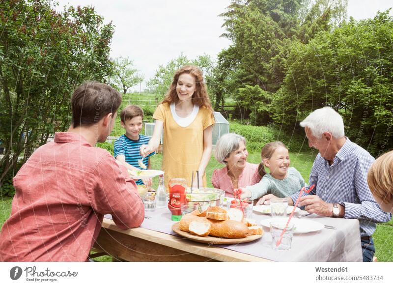 Fröhliche Großfamilie beim Essen im Garten Gärten Gaerten Generationen glücklich Glück glücklich sein glücklichsein Familie Familien essen essend Mensch