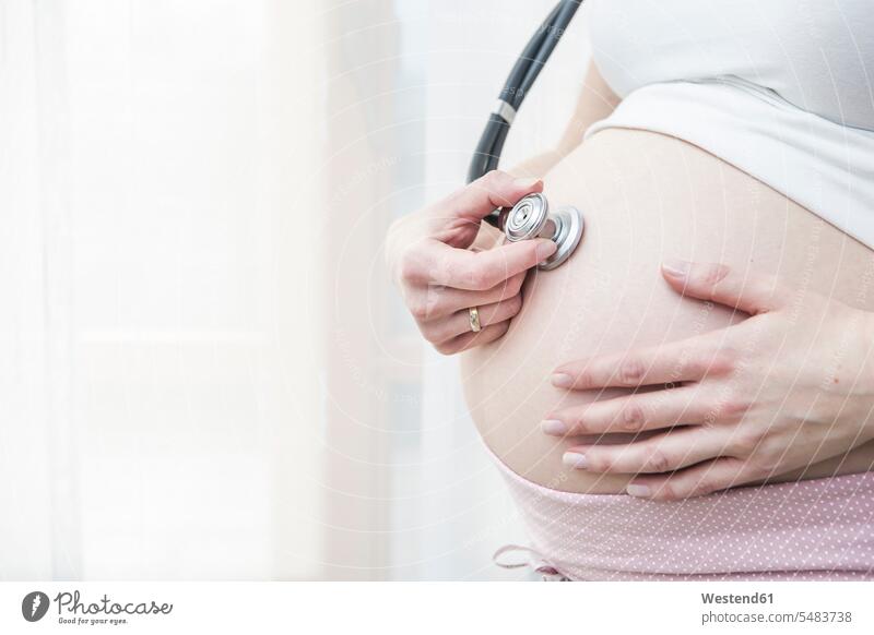 Schwangere Frau hält Stethoskop vor ihren Bauch Europäer Kaukasier Europäisch kaukasisch Bäuche Mittlerer Ausschnitt Mittlere Ausschnitte Textfreiraum