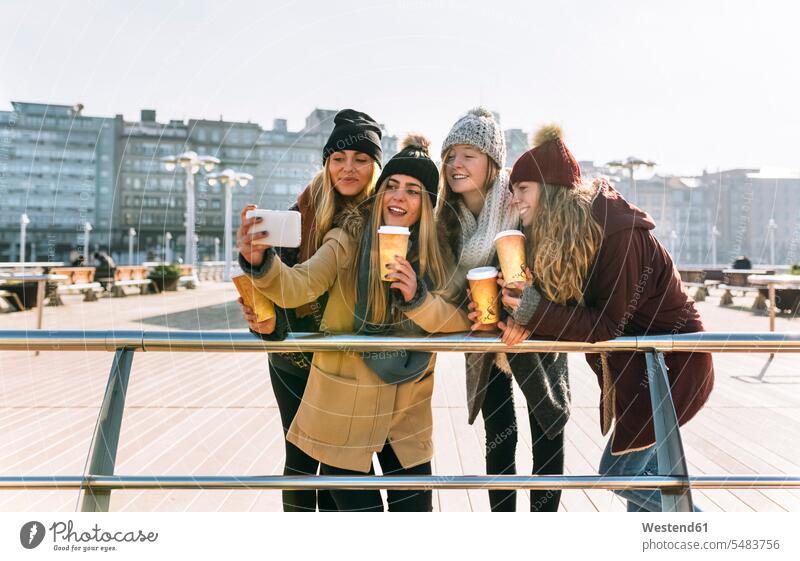 Vier Freunde mit Kaffee zum Mitnehmen, die ein Selfie mit Smartphone machen Kameradschaft Freundin Selfies Essen Essen und Trinken Food Lebensmittel