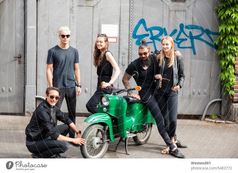 Gruppe von fünf schwarz gekleideten Freunden mit grünem Moped 20-25 Jahre 20 bis 25 Jahre 20 - 25 Jahre junge Frau junge Frauen junger Mann junge Männer