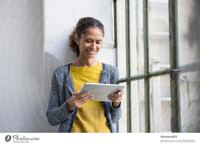 Junge Frau steht am Fenster und benutzt ein digitales Tablett stehen stehend lesen Lektüre Tablet Computer Tablet-PC Tablet PC iPad Tablet-Computer weiblich