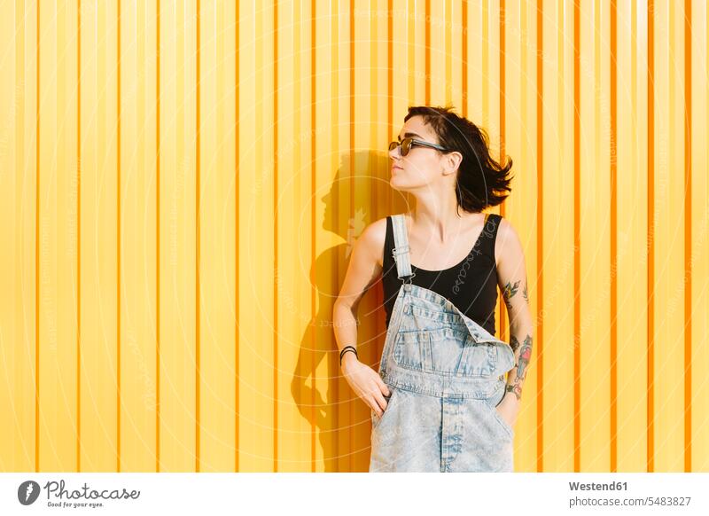 Junge Frau, die an einer gelben Wand steht Europäer Kaukasier Europäisch kaukasisch braune Haare braunhaarig brünett braunes Haar gelber gelbes Schatten