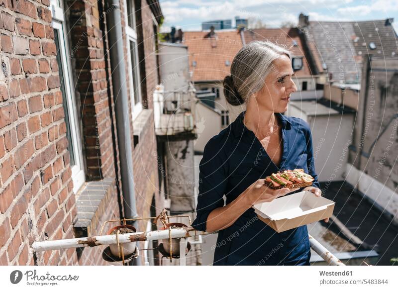Geschäftsfrau auf dem Balkon macht Mittagspause essen essend Geschäftsfrauen Businesswomen Businessfrauen Businesswoman Balkone Frau weiblich Frauen