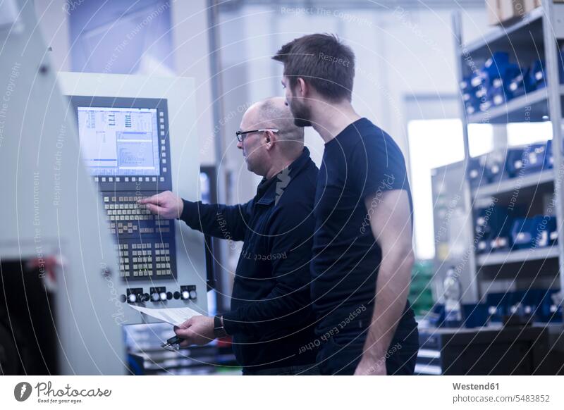 Zwei Männer bedienen eine Maschine in einer Fabrik arbeiten Arbeit Mann männlich Erwachsener erwachsen Mensch Menschen Leute People Personen Beruf